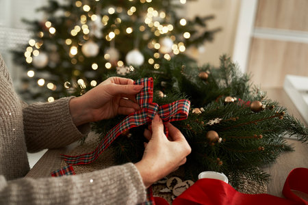 Unrecognizable woman preparing ribbon for Christmas decorationsの写真素材