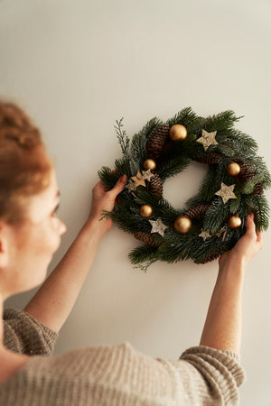 Woman hanging a Christmas wreath on the wallの写真素材