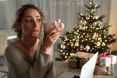 Caucasian woman looking for some money into a piggy bankの写真素材