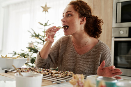 Caucasian woman tasting homemade gingerbread cookies in the kitchenの写真素材