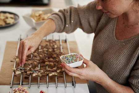 Caucasian woman decorating Christmas cookies with sugar sprinklesの写真素材