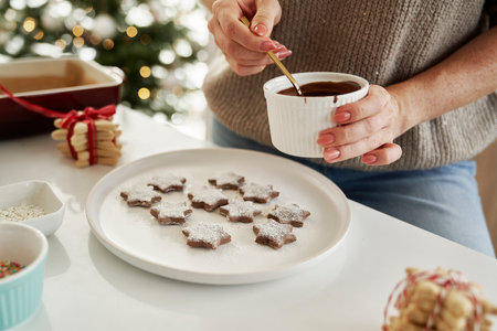 Unrecognizable woman decorating Christmas cookies with a chocolate glazeの写真素材
