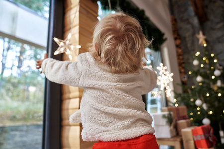 Back view of toddler in house decorated for Christmasの写真素材