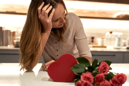 Sad woman looking at box of chocolates and bunch of rosesの写真素材