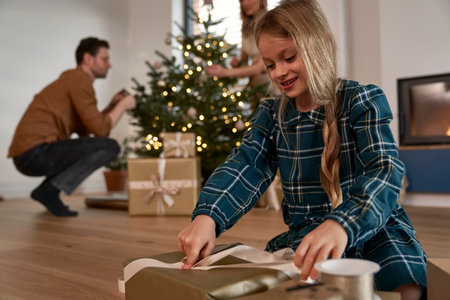 Caucasian girl packing Christmas presents next to Christmas treeの写真素材