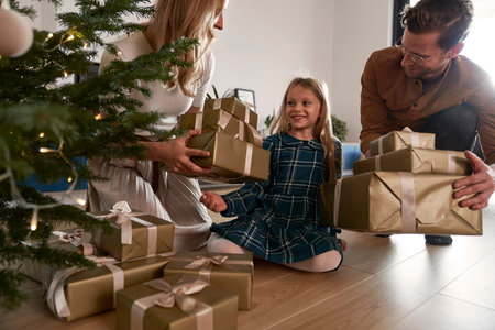 Cheerful parents sharing Christmas presents with their daughterの写真素材