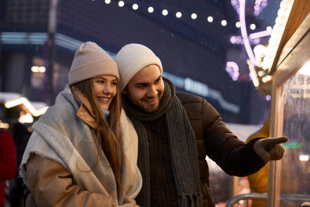 Caucasian couple having fun on Christmas market at nightの写真素材