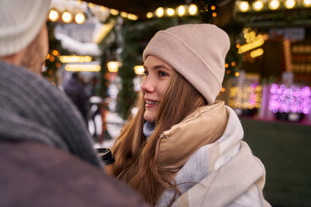 Caucasian woman drinking mulled and chatting with a friend on Christmas marketの写真素材