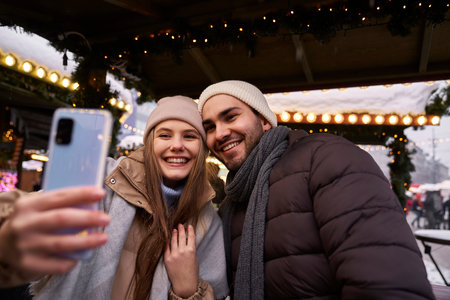 Young couple taking selfie on Christmas Market at nightの写真素材