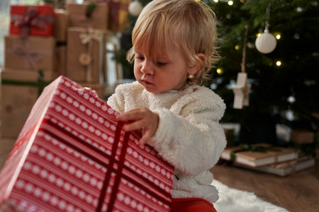 Cheerful caucasian toddler unpacking Christmas presentの写真素材