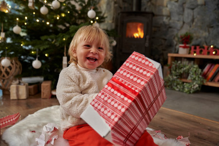 Cheerful caucasian toddler unpacking Christmas presentの写真素材