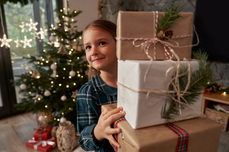 Elementary age girl carrying a pile of Christmas presentsの写真素材