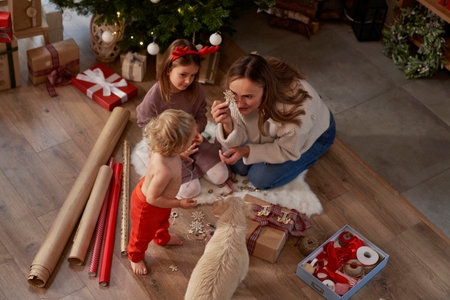 High angle view of mother and children wrapping Christmas gifts on the floorの写真素材