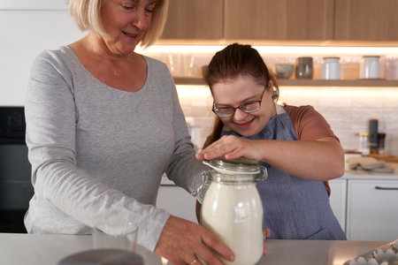 Down syndrome woman and her mother baking togetherの写真素材