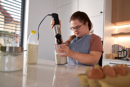 Down syndrome woman baking in domestic kitchenの写真素材