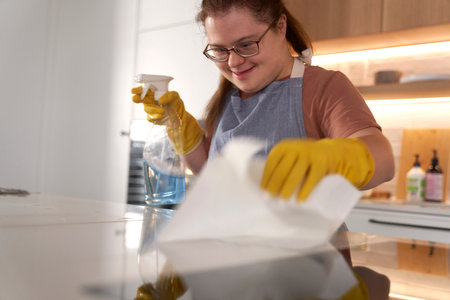 Down syndrome woman cleaning worktop in domestic kitchenの写真素材