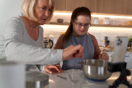 Down syndrome woman and her mother using recipe on the phoneの写真素材