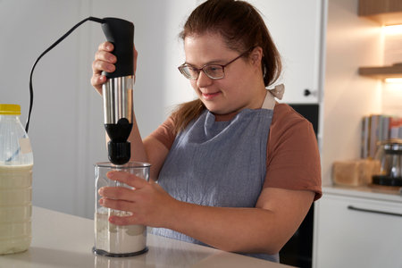 Down syndrome woman baking in domestic kitchenの写真素材