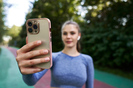 Woman in sportswear on track holding a mobile phoneの写真素材