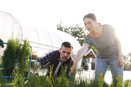Worker advising the client over plants in garden centerの写真素材