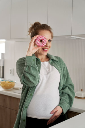 Pregnant woman having fun with a donutの写真素材