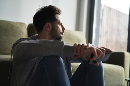 Anxious man at home sitting on floorの写真素材