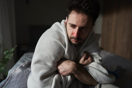 Ill man sitting under the blanketの写真素材