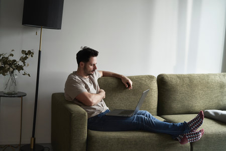Man working on laptop on sofaの写真素材