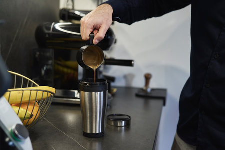 Man pouring homemade coffee into the travel mugの写真素材