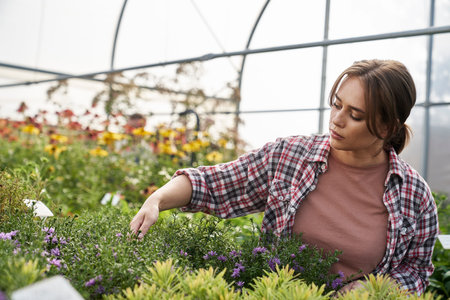 Caucasian female botanist working in greenhouse over flowersの写真素材