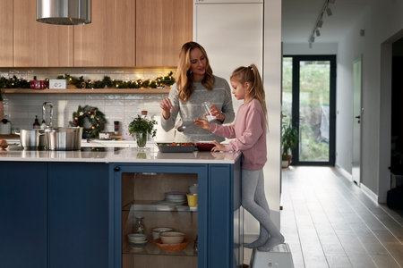 Caucasian daughter and mother preparing food before Christmasの写真素材