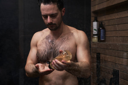 Caucasian man using shampoo under the shower