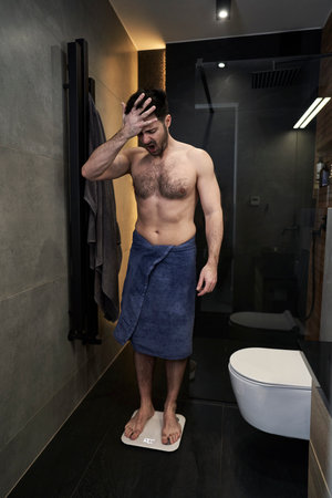 Shocked man using bathroom scaleの写真素材