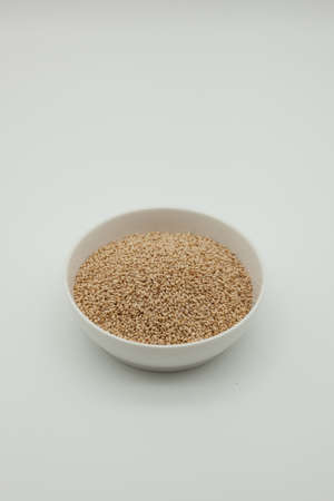 Sesame seeds in a bowl on a white backgroundの写真素材