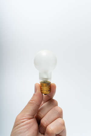 Asian hand holding an incandescent light bulbの写真素材