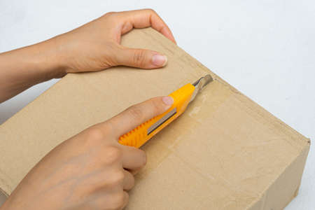 Unboxing the courier box with a cutter knifeの写真素材