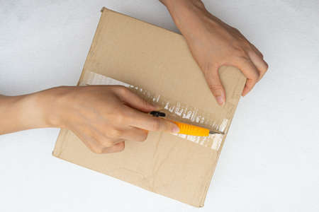 Unboxing the courier box with a cutter knifeの写真素材