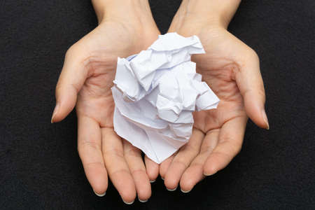 A mess of crumpled paper trash on a black backgroundの写真素材