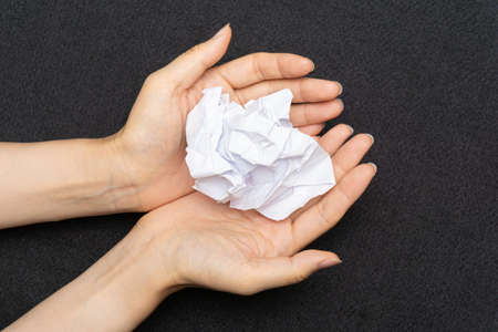 A mess of crumpled paper trash on a black backgroundの写真素材