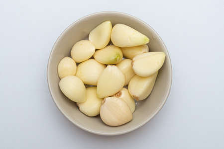 Garlic in a bowl on a white backgroundの写真素材