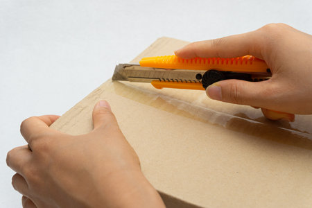 Unboxing the courier box with a cutter knifeの写真素材