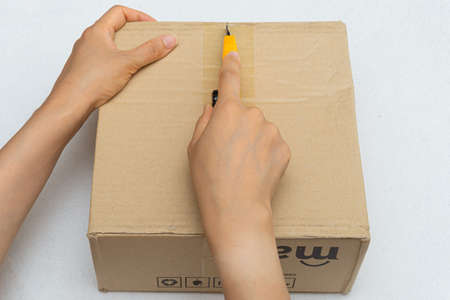 Unboxing the courier box with a cutter knifeの写真素材