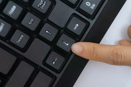 A woman's finger holding a computer keyboardの写真素材