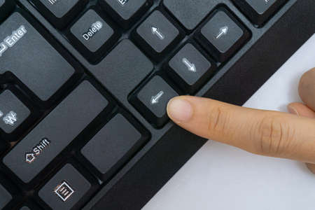 A woman's finger holding a computer keyboardの写真素材