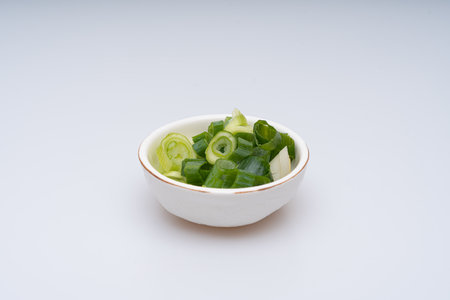 Green onion being trimmed on a white backgroundの写真素材