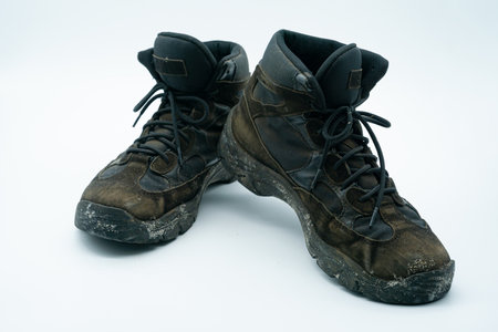 Old dirty sand and black work shoes with dirt on a white backgroundの写真素材