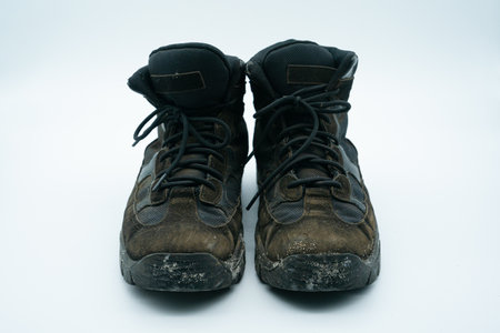 Old dirty sand and black work shoes with dirt on a white background