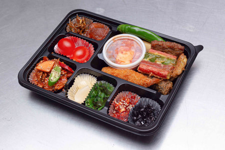 A delicious-looking lunch box with a variety of side dishes, fruits and tempuraの写真素材