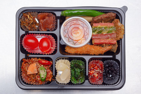 A delicious-looking lunch box with a variety of side dishes, fruits and tempuraの写真素材
