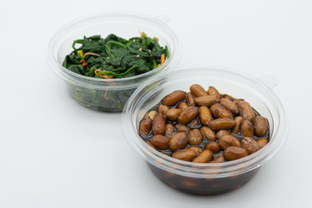 Stir-fried soybeans with spinach in plastic container on white backgroundの写真素材